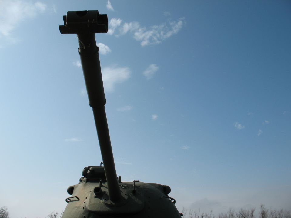 Tank turret and gun pointing up against a blue sky with clouds. Supermotors.net logo visible