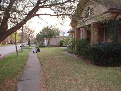 1996 Ford Taurus - A person sits on the grass by a sidewalk on a residential street.