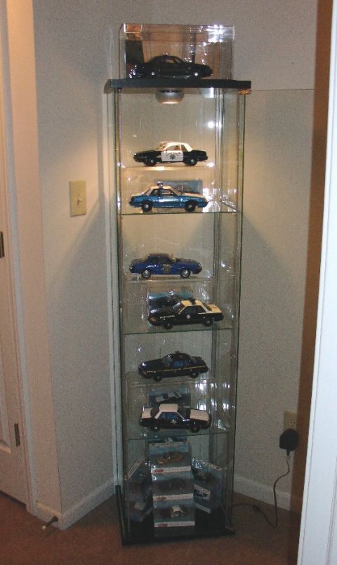 2003 Ford Crown Victoria - A glass display case filled with various police car models, including several Ford Crown Victorias.