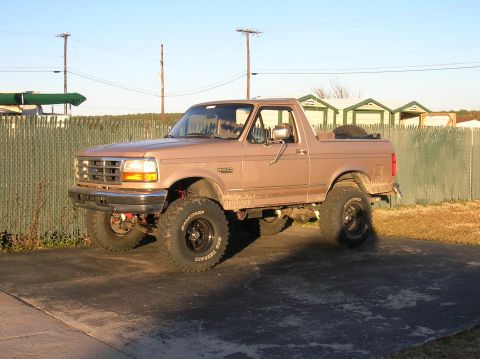 1996 Ford Bronco - A lifted 1996 Ford Bronco with off-road tires is parked outside on a sunny day.