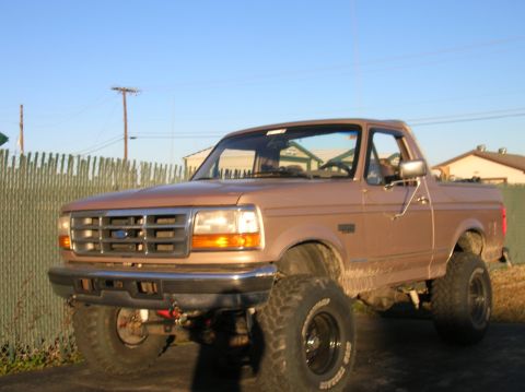 1996 Ford Bronco - This lifted Ford pickup truck is shown from a three-quarter front view under a clear sky.