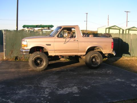 1996 Ford Bronco - A lifted 1996 Ford Bronco with off-road tires is parked on a paved surface.