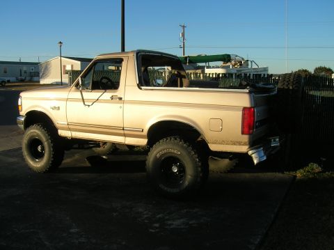 1996 Ford Bronco - This tan Ford Bronco features a removable soft top and is seen from the side.