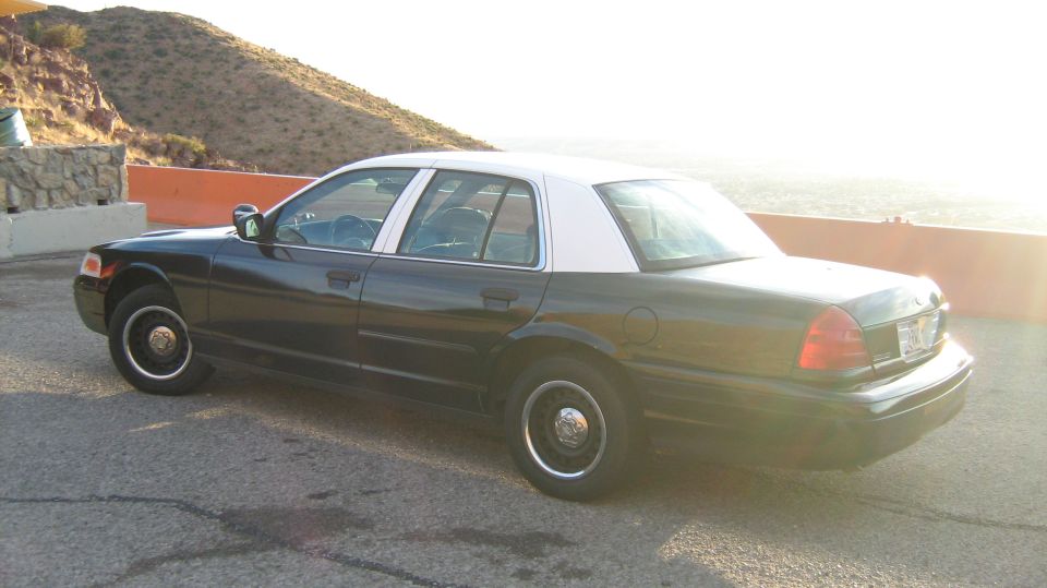 Dark green Ford Crown Victoria sedan parked on a desert overlook