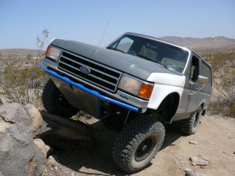 1988 Ford Bronco - This modified Ford Bronco is navigating a challenging off-road course in a desert environment.