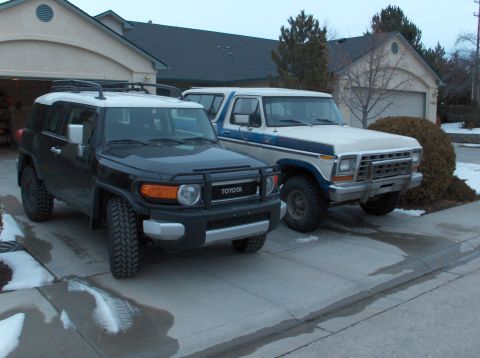 2008 Toyota FJ Cruiser - A black Toyota FJ Cruiser and a vintage Ford Bronco are parked side-by-side in a suburban driveway.