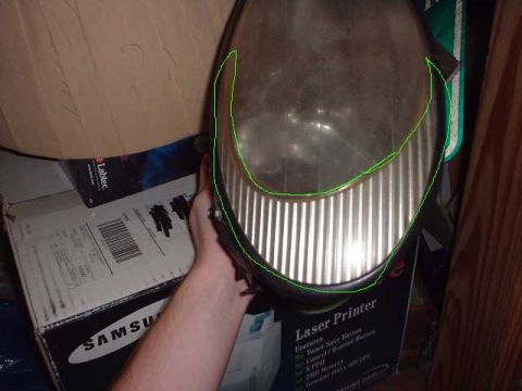 1996 Ford Taurus - A headlight assembly is held up, with boxes and a printer visible in the background.