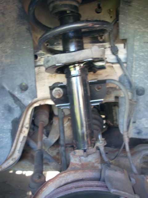1991 Ford Taurus - Close-up view of a vehicle's front suspension system, showing the strut, coil spring, and associated hardware.