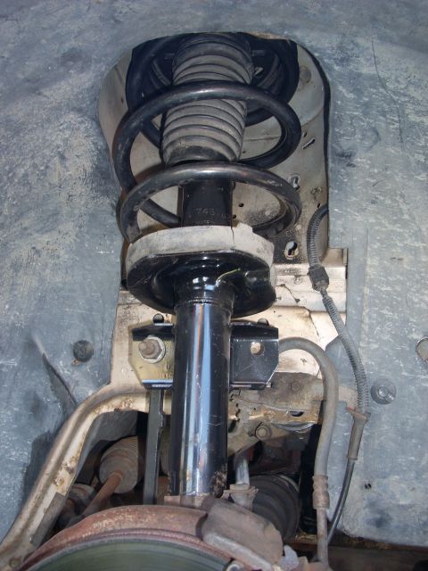 1991 Ford Taurus - Close-up of a vehicle's front strut assembly, showing the coil spring and shock absorber.