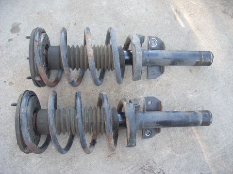 1991 Ford Taurus - Two used front strut assemblies are shown laid out on a concrete surface.