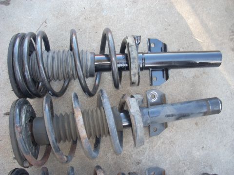 1991 Ford Taurus - Comparison of two front struts, one appearing newer and the other showing significant rust and wear.