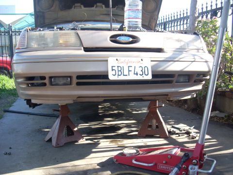 1991 Ford Taurus - Front view of a 1991 Ford Taurus undergoing maintenance, supported by jack stands.