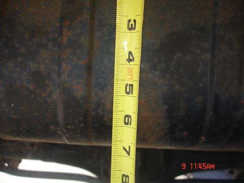 1979 Ford Bronco - A tape measure is used to gauge the size of a dark, rusty vehicle component.
