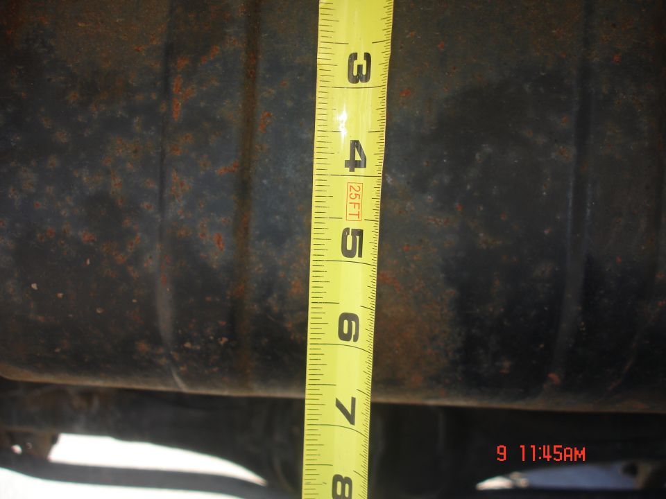 measuring tape against rusty metal part of a vehicle