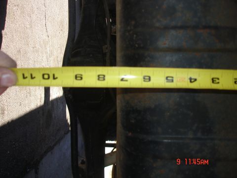 1979 Ford Bronco - A yellow measuring tape is held over a dark, cylindrical suspension component.