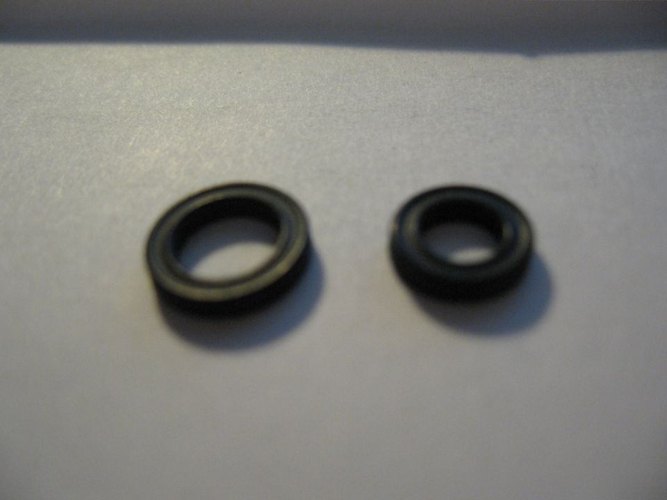 Two rubber O-rings, one larger with a yellow stripe, on a gray surface