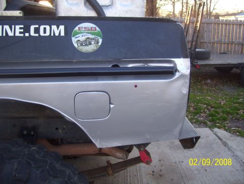 1978 Ford Bronco - Close-up of a truck's rear quarter panel, showing a gas cap door and a sticker with an off-road vehicle graphic.