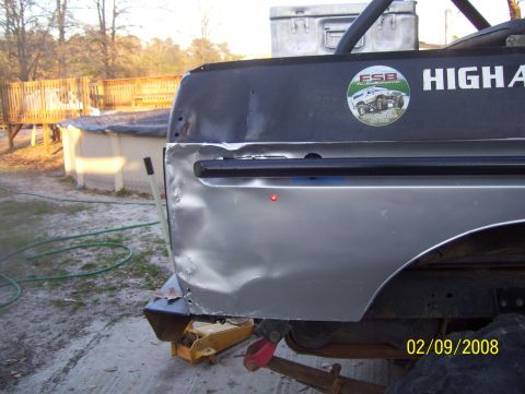1978 Ford Bronco - The rear quarter panel of a vehicle shows significant damage and a sticker with text and an image of an off-road vehicle.