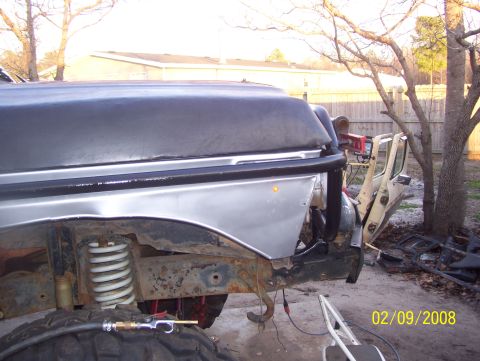 1978 Ford Bronco - A close-up view shows the fender and open door of a vehicle, revealing suspension components and a large tire.