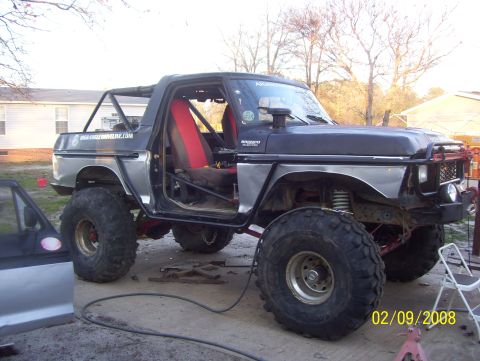 1978 Ford Bronco - Modified 1978 Ford Bronco with roll cage and off-road tires sits outside.
