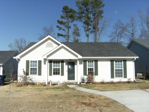 1992 Ford F-150 - Front exterior of a single-story white vinyl-sided house with sage green shutters, dark shingle roof, gabled entry porch and a concrete wal…