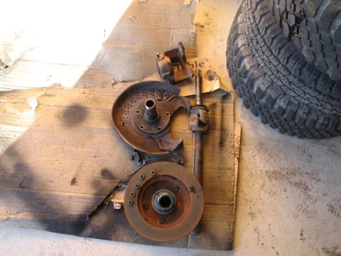 1995 Ford Bronco - Vehicle brake and drivetrain components are shown disassembled on a cardboard surface.
