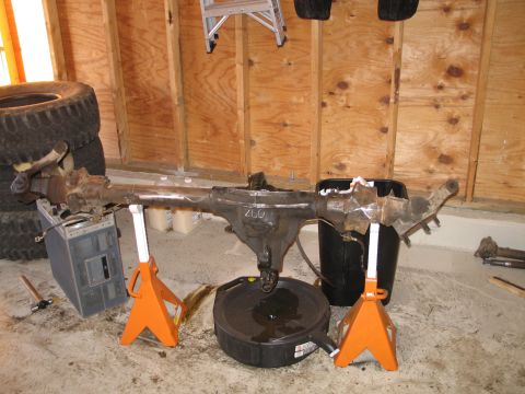 1995 Ford Bronco - A vehicle axle assembly is supported by jack stands in a garage setting.