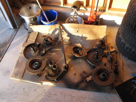 1995 Ford Bronco - Various disassembled vehicle parts, including brake rotors and suspension components, are arranged on a piece of cardboard.