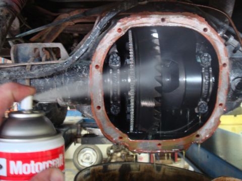1996 Ford Bronco - Mechanic sprays cleaner into the differential of a vehicle, with a Motorcraft can in view.