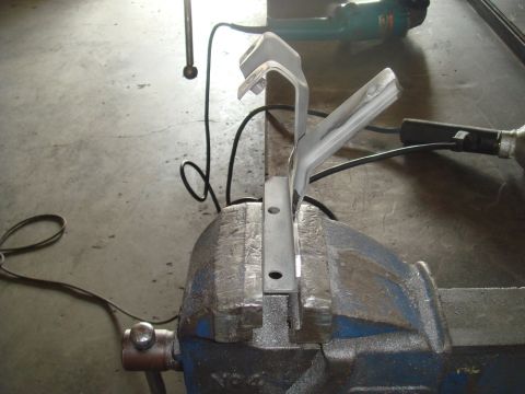 1996 Ford Bronco - A metal bracket is secured in a vise, ready for modification with power tools visible nearby.