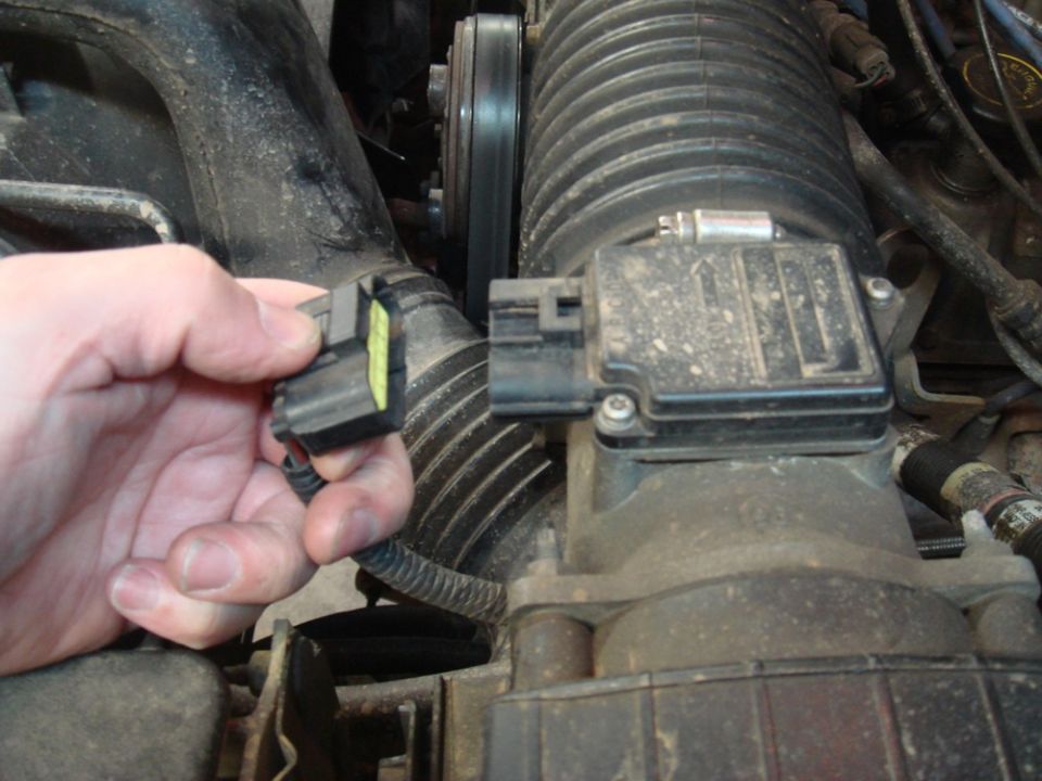Hand disconnecting electrical connector from engine air intake sensor