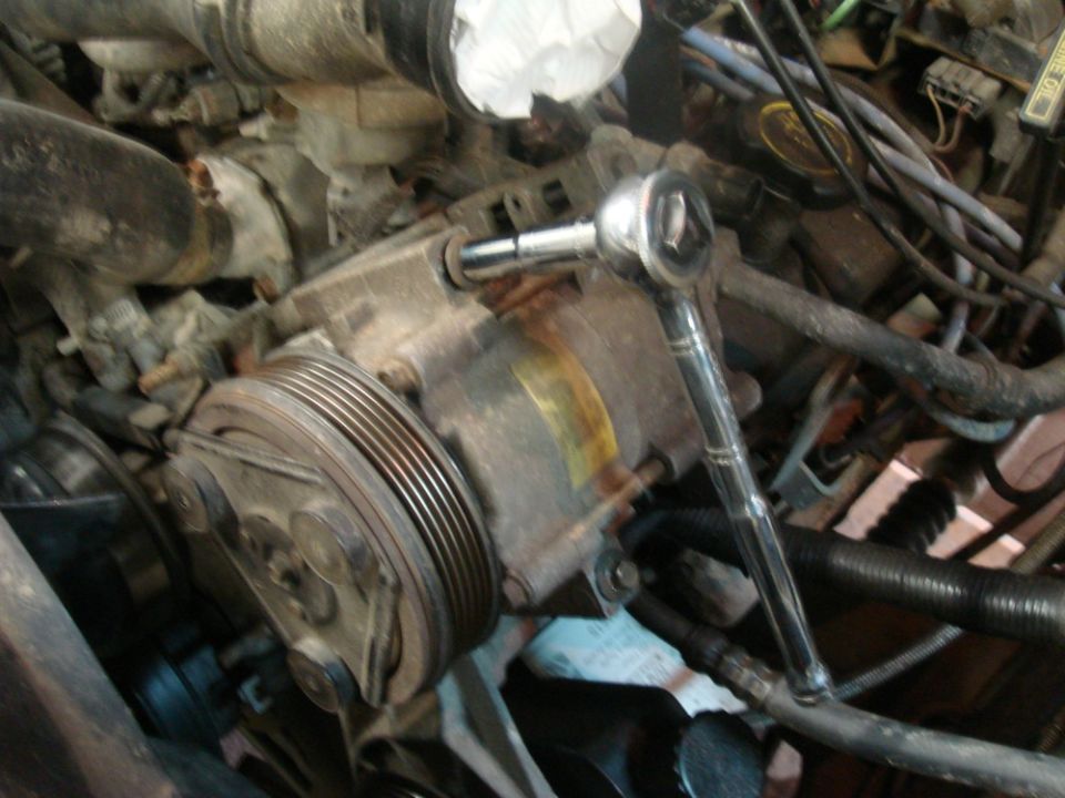 Close-up of a rusty engine component with a socket wrench attached
