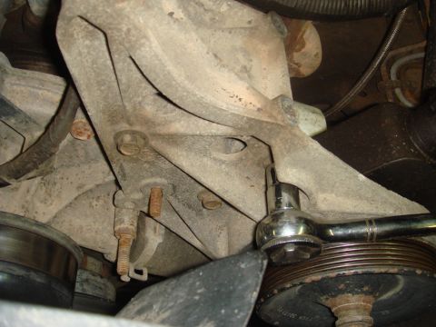 1996 Ford Bronco - Close-up of a vehicle's power steering pump bracket with a socket wrench attached to a bolt.