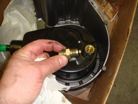 1996 Ford Bronco - A hand holds a brass fitting near a black pump housing, possibly for a Saginaw Pump II.
