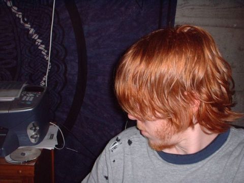 1996 Ford Taurus - A person with red hair and a beard is seen from the side, wearing a grey t-shirt with some dark marks on it.
