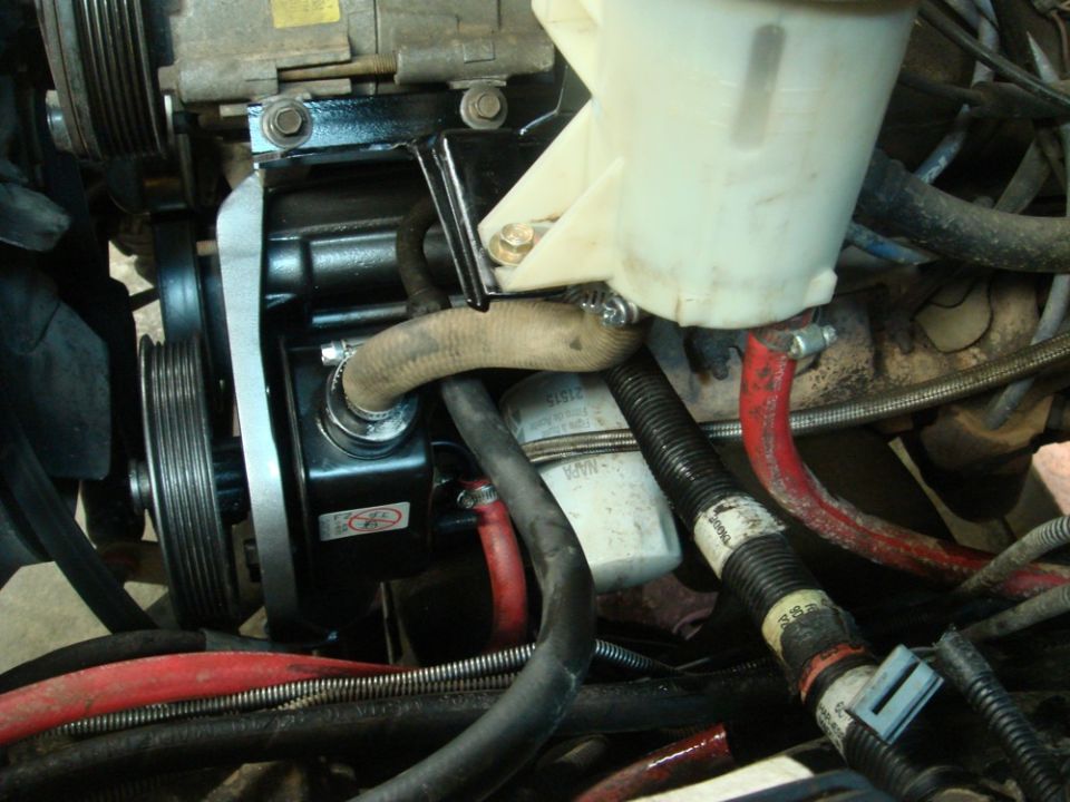 Power steering pump and reservoir with hoses and belts visible