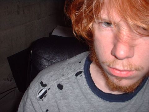 1996 Ford Taurus - Person with red hair and beard wearing a torn t-shirt. 'SUPERMOTORS' logo is visible.