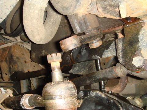 1996 Ford Bronco - Undercarriage view of greasy and corroded vehicle steering and suspension components.