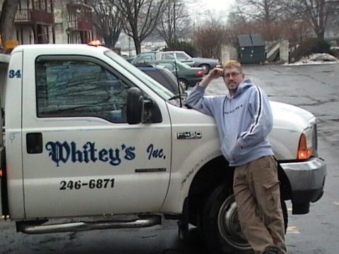 1990 Ford Bronco - Man poses with a white Ford F-350 truck that has company text on the door.