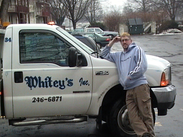 White Ford F-350 truck with 'Whitey's Inc.' and phone number on door; man leaning on fender