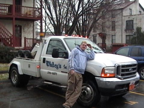 1990 Ford Bronco - A man poses next to a white tow truck with "Whitey's Inc." written on the side.