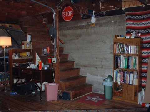 1996 Ford Taurus - A cluttered basement scene features a wooden staircase, a desk with items, and a bookshelf filled with books.
