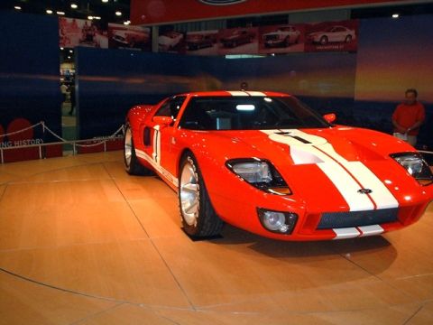 1996 Ford Taurus - A bright red 2005 Ford GT with iconic white racing stripes is displayed at an auto show.