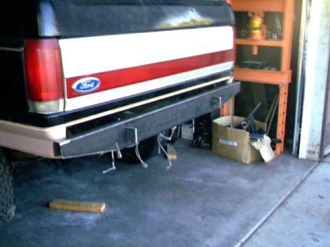 1989 Ford Bronco - The rear of a Ford truck is shown with a custom bumper and a red and white stripe on the tailgate.