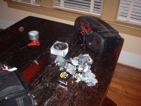 1996 Ford Taurus - A black electronic device with red accents sits on a cluttered wooden table next to tape and scissors.