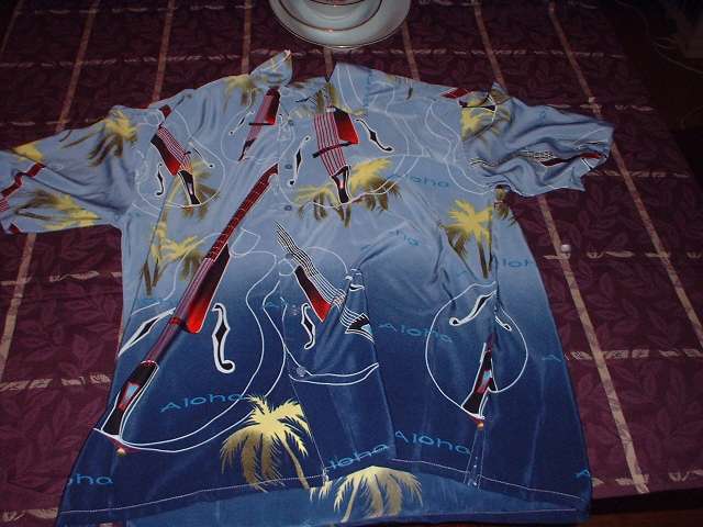 Hawaiian shirt with guitars and palm trees on a bed
