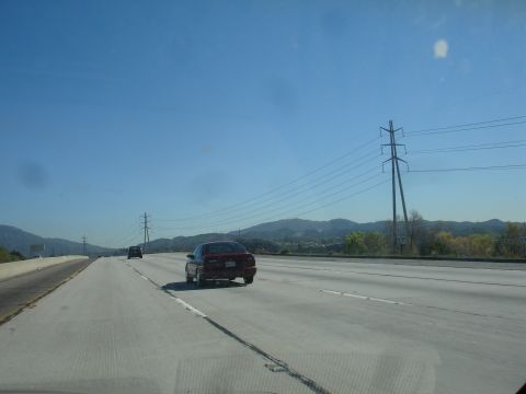 1991 Ford Taurus - A red sedan travels down a multi-lane highway under a clear blue sky.