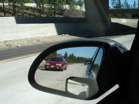 1991 Ford Taurus - Red 1991 Ford Taurus driving on highway, seen from side mirror.