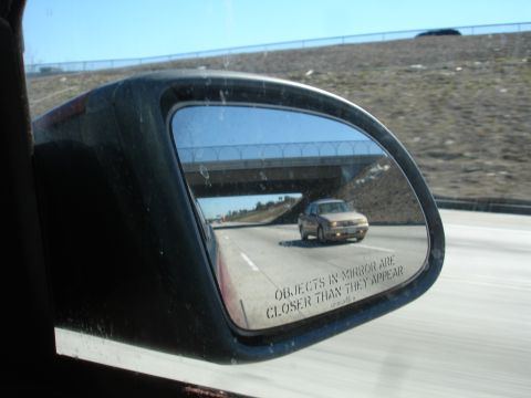 1991 Ford Taurus - A tan sedan is seen in the side mirror of another vehicle on the highway.