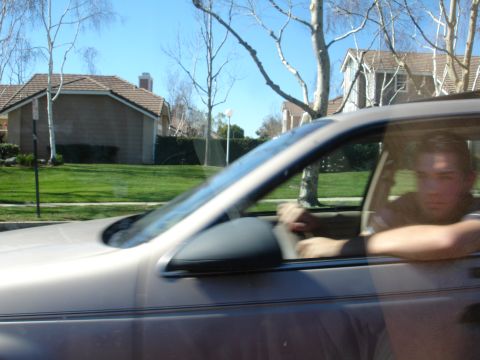 1991 Ford Taurus - Driver seen from the side, looking out the window of a moving car.